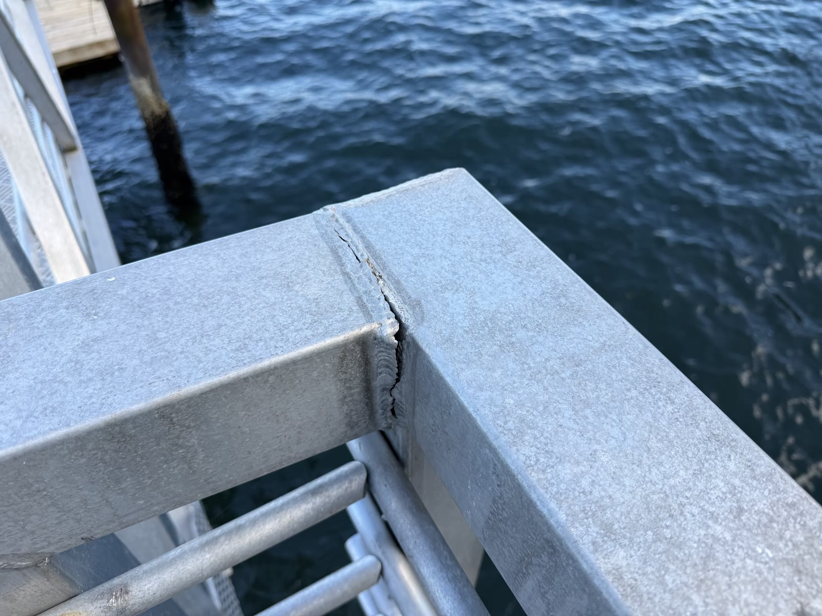 Cracked aluminum gangway railing corner above the water before repair