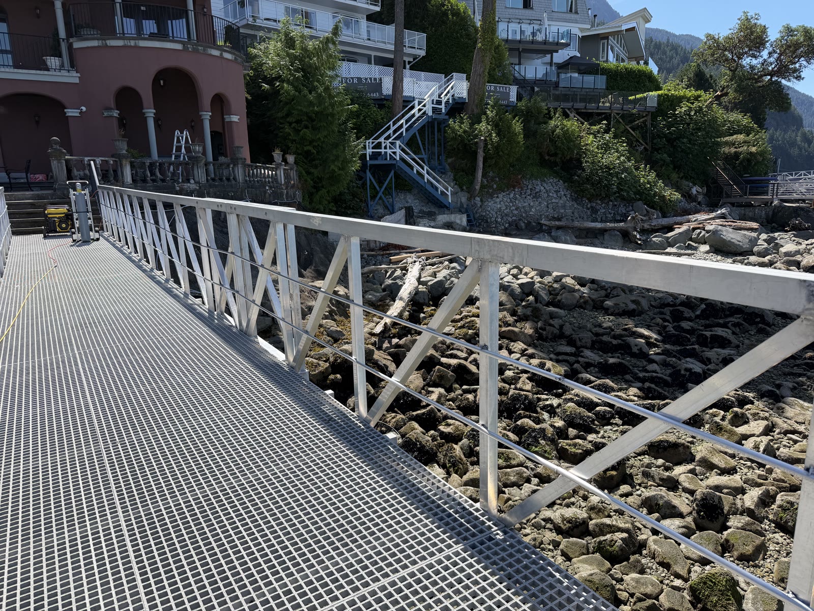 Completed aluminum gangway railing beside rocky shoreline